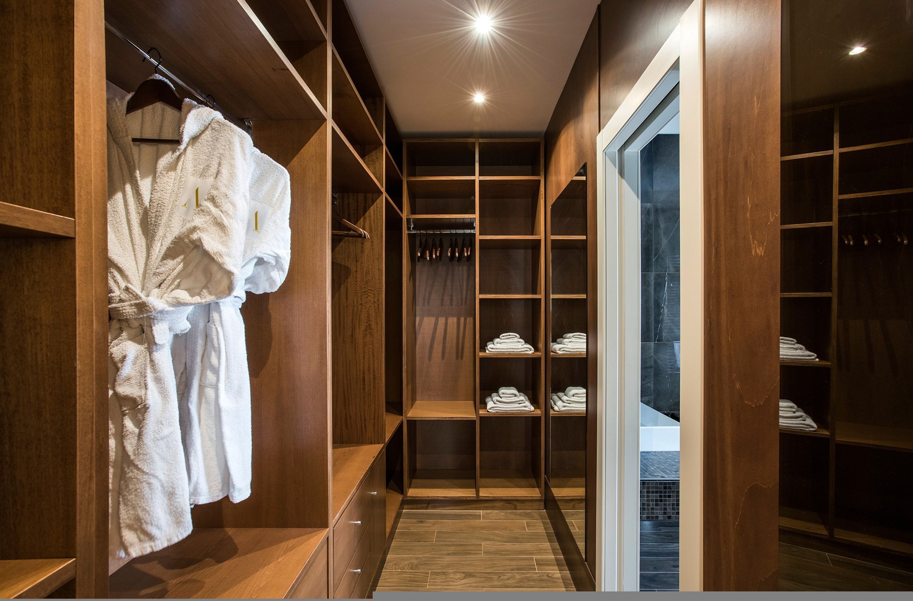 A walk-in closet with wooden shelving and a robe hanging on the left.
