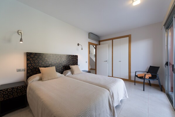 A bedroom with two beds, a chair, a nightstand, and a wardrobe. - Villa in Maspalomas With Heated Pool & Golf Views (San Bartolomé de Tirajana)