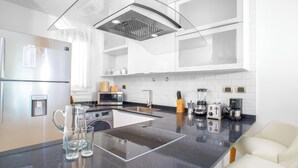 A modern kitchen with a central island, stainless steel appliances, and a sleek design. - Cana Rock Condos (Punta Cana)