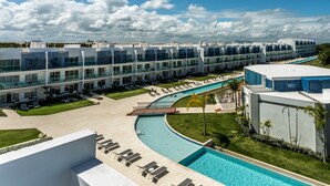 A modern hotel with a swimming pool, multiple balconies, and a well-maintained lawn. - Cana Rock Condos (Punta Cana)