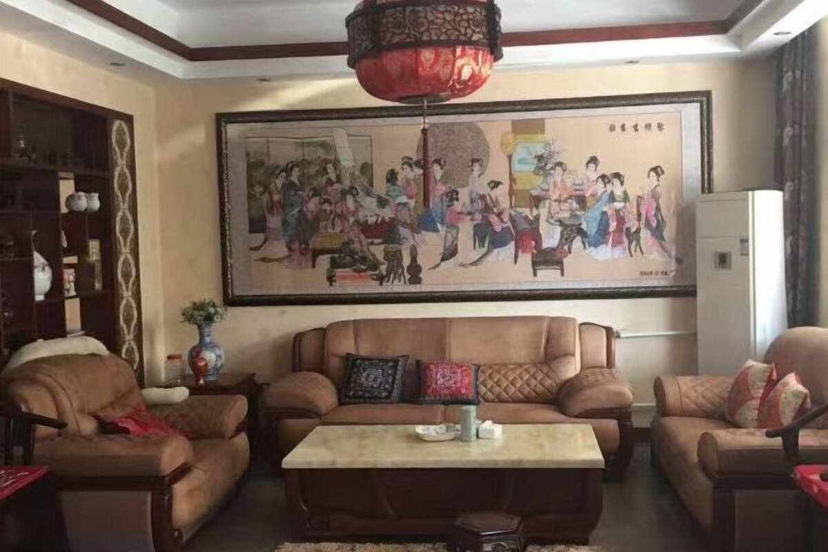 Un salon agrémenté d’un grand tableau de style traditionnel, de canapés en cuir, d’une table basse et d’un luminaire décoratif suspendu.