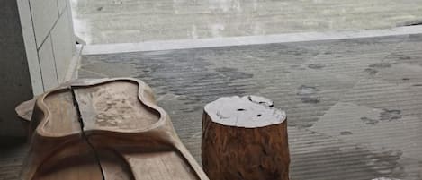 A wooden bench and two tree stump stools on a concrete floor with a wet surface.