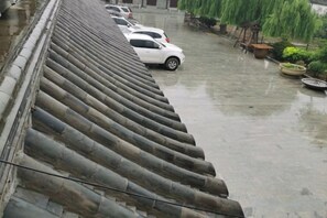 A parking area with cars and a building with a tiled roof. - Xinzhuang Seafood Hotel (Zhaoyuan)