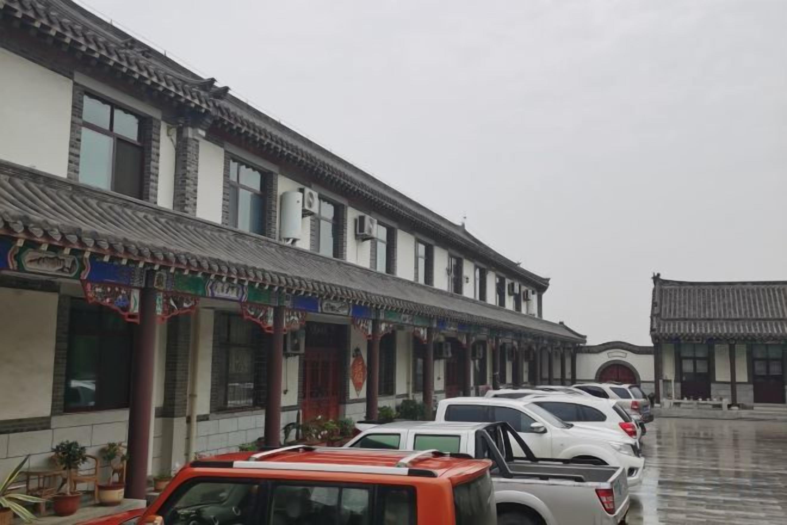 Il s’agit d’un bâtiment traditionnel, doté d’un toit en tuiles et d’une cour intérieure. Des voitures sont garées devant le bâtiment.