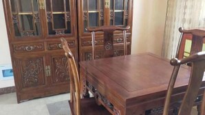 Una mesa de comedor de madera con sillas, un aparador con puertas de vidrio y una alfombra en el suelo.