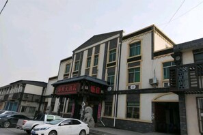 Un edificio de varios pisos con un local comercial en la planta baja, que presenta señalización y un acceso cubierto.