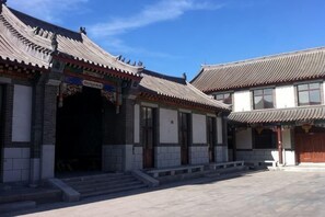 Un edificio tradicional con tejado de tejas, entrada central y un patio.