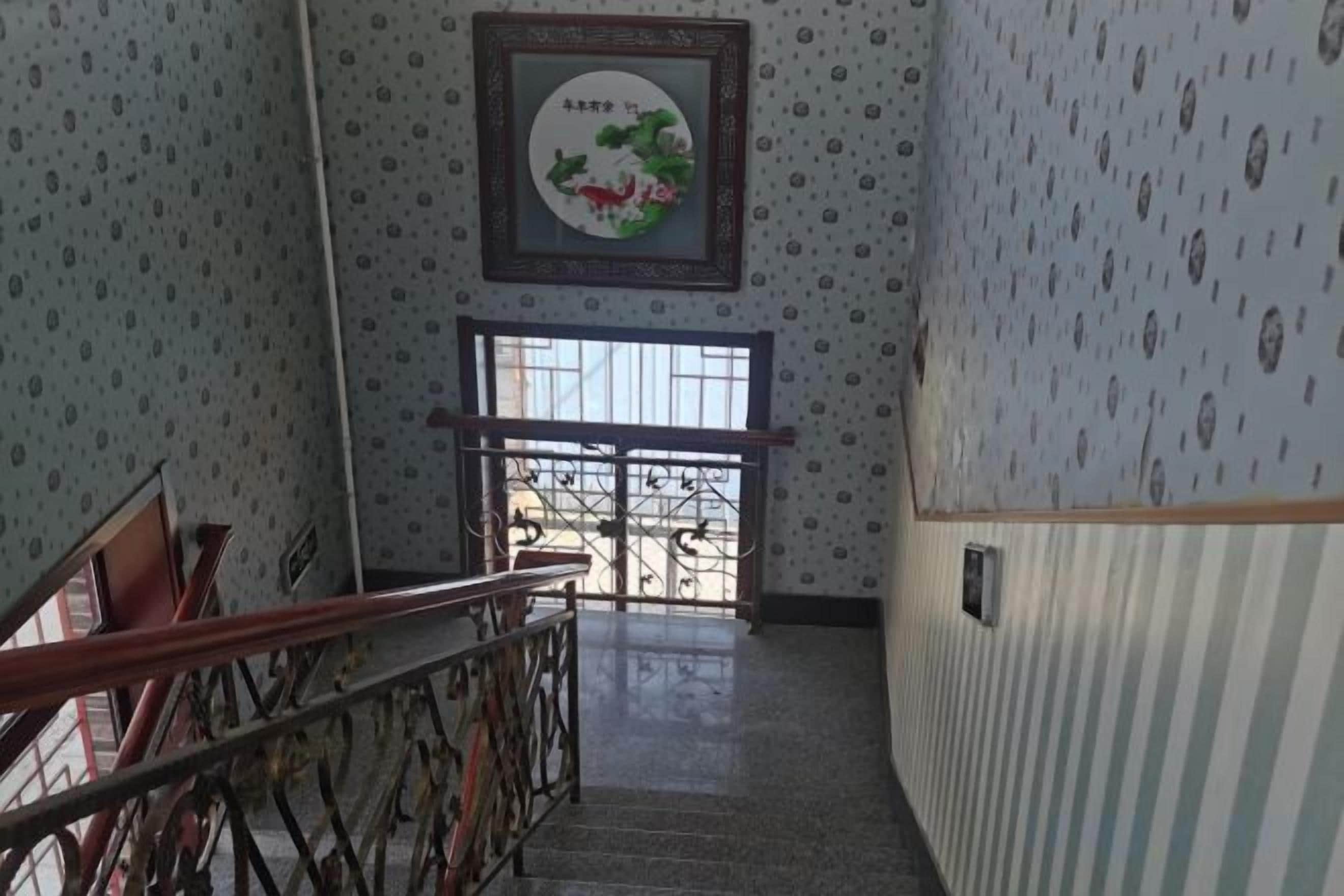 Una escalera con barandilla, una puerta al final e interesante papel tapiz.