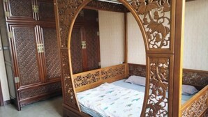 Una cama con dosel adornada con intrincados grabados de madera, un armario a juego y una colcha estampada.