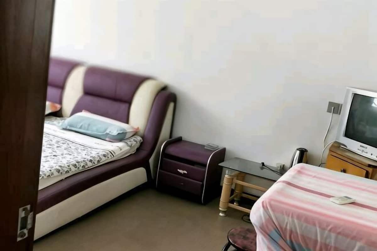 Une chambre à coucher avec un lit, une télévision, une petite table et une chaise.