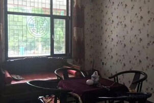 Una habitación con ventana, sofá, mesa de comedor con sillas y pared decorada.