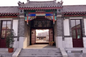 Entrada a un edificio chino tradicional con tejado de tejas, un arco decorativo y una escalera que conduce a la entrada.