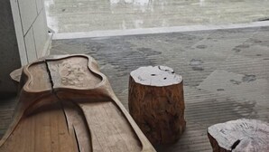 Un banco de madera y un tocón de árbol en un espacio al aire libre con el suelo mojado, lo que sugiere lluvia reciente.