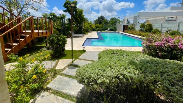 Ein Garten mit Schwimmbad, einer Holztreppe und verschiedenen Pflanzen.