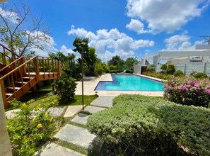 A backyard with a swimming pool, a wooden staircase, and various plants. - Escape to Villa Casita in lovely Punta Cana with private pool, WiFi, AC & more! (Punta Cana)