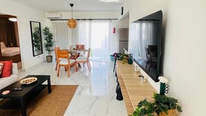 Ein modernes Wohnzimmer mit Sofa, Couchtisch, Fernseher und Essbereich.