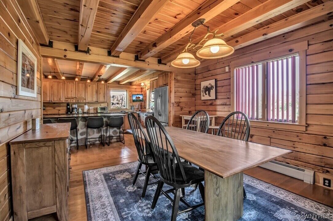 A wooden cabin interior with a dining area, kitchen, and bar.