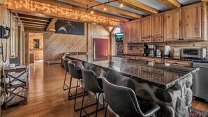 Una cocina moderna con armarios de madera, una isla grande con taburetes de bar y una pared decorativa de piedra.