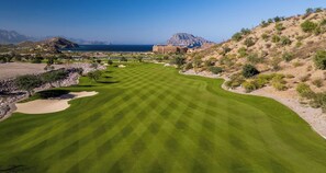 A golf course with a view of a mountain and a body of water in the background.