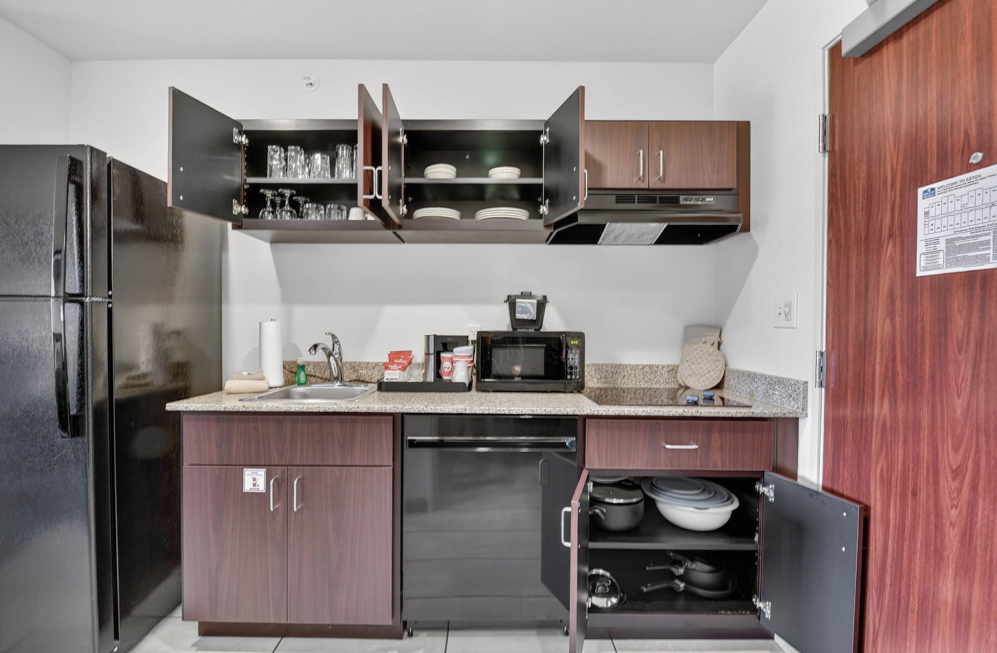 A compact kitchen with a refrigerator, microwave, and built-in oven.