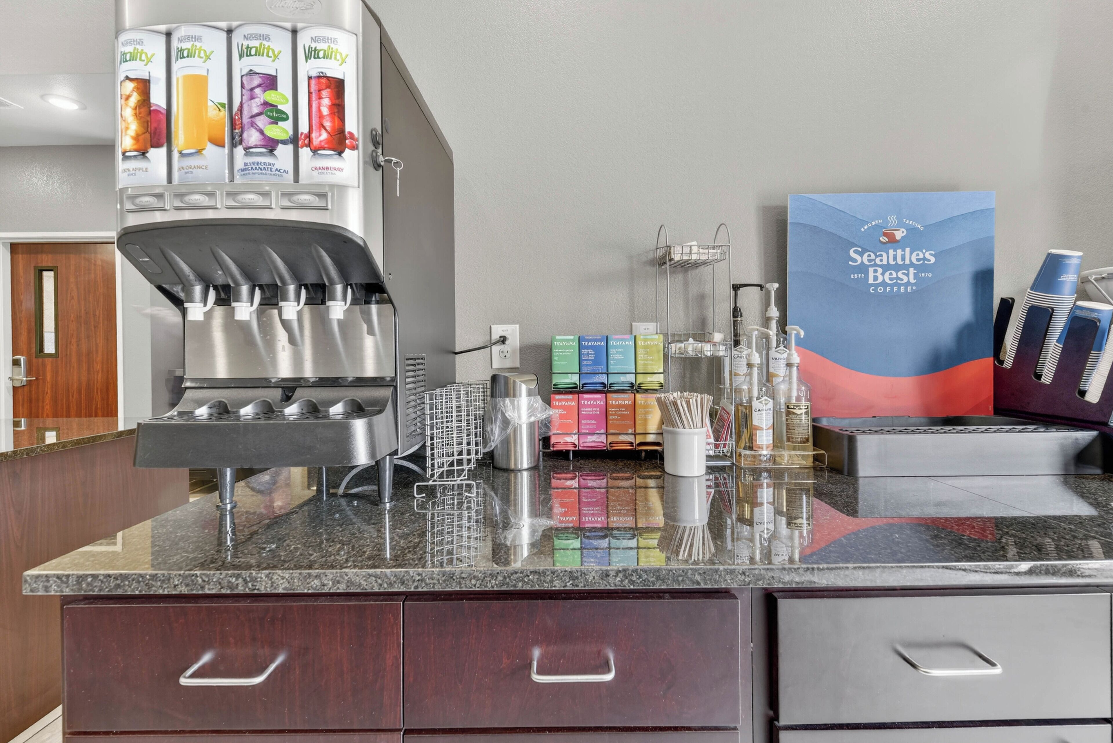 Een koffiehoek met een drankenspender, een koffieapparaat en een bord met Seattle's Best Coffee.