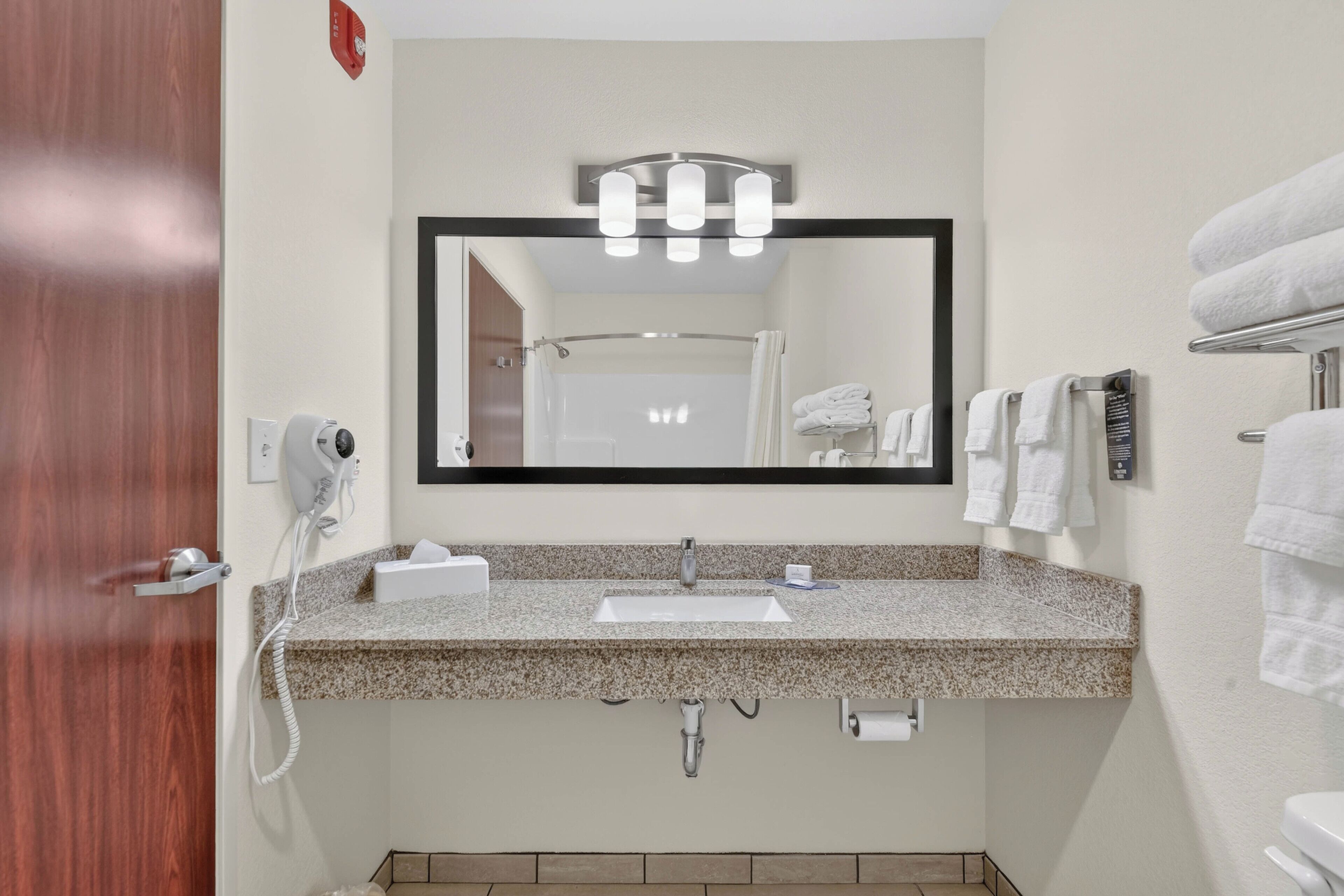 Une salle de bain équipée d’un lavabo, d’un miroir, d ’un porte-serviettes et d’un sèche-cheveux.