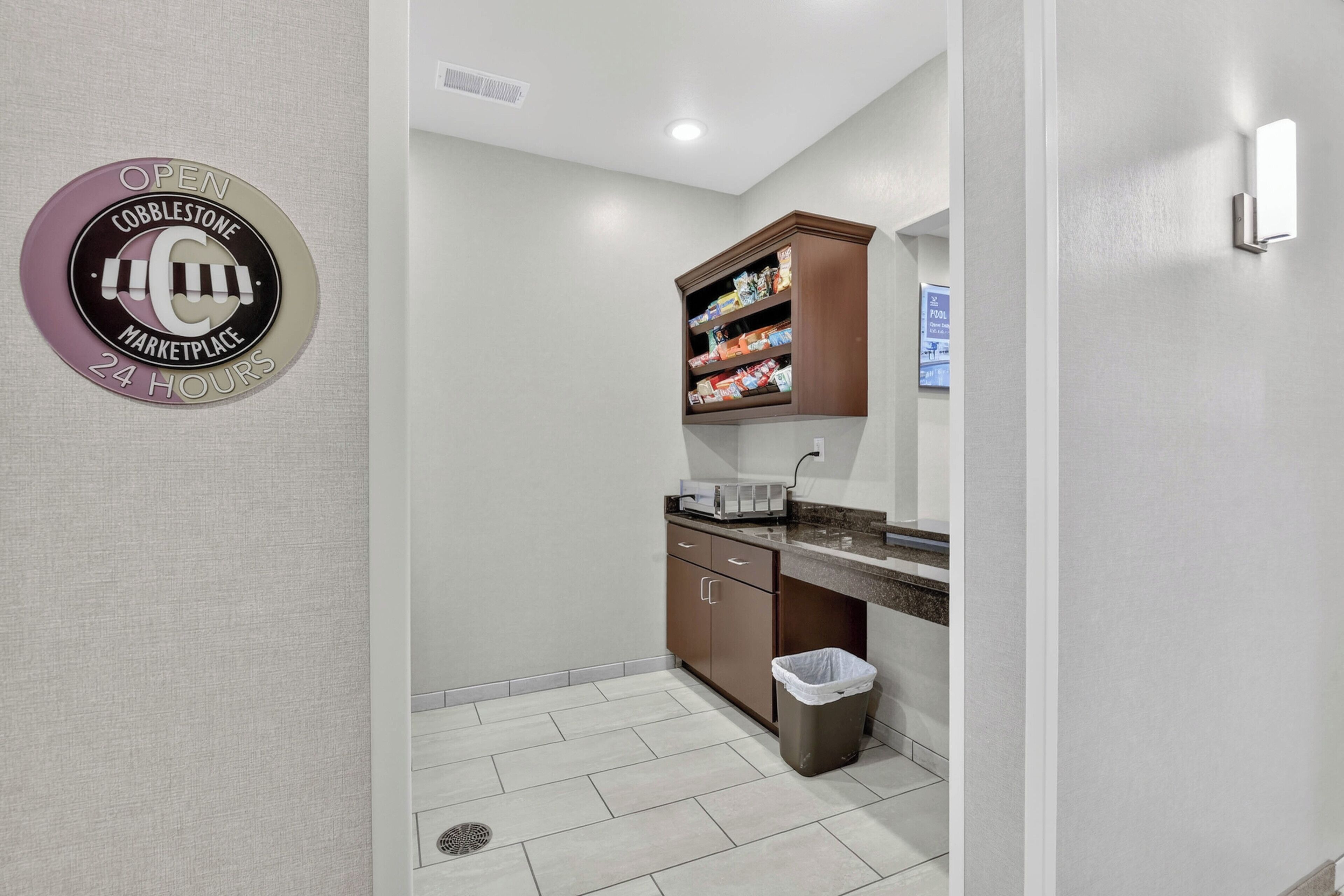 A kitchenette with a trash bin, a countertop, and a cabinet with snacks.