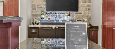 A bar area with a stone wall, a flat-screen TV, and a menu sign.