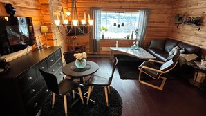 L’intérieur d’un chalet confortable, avec une salle à manger, un canapé et un téléviseur.