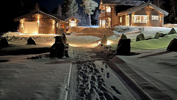 Une cabane en rondins dotée d’un grand porche à l’avant et d’une allée recouverte de neige.