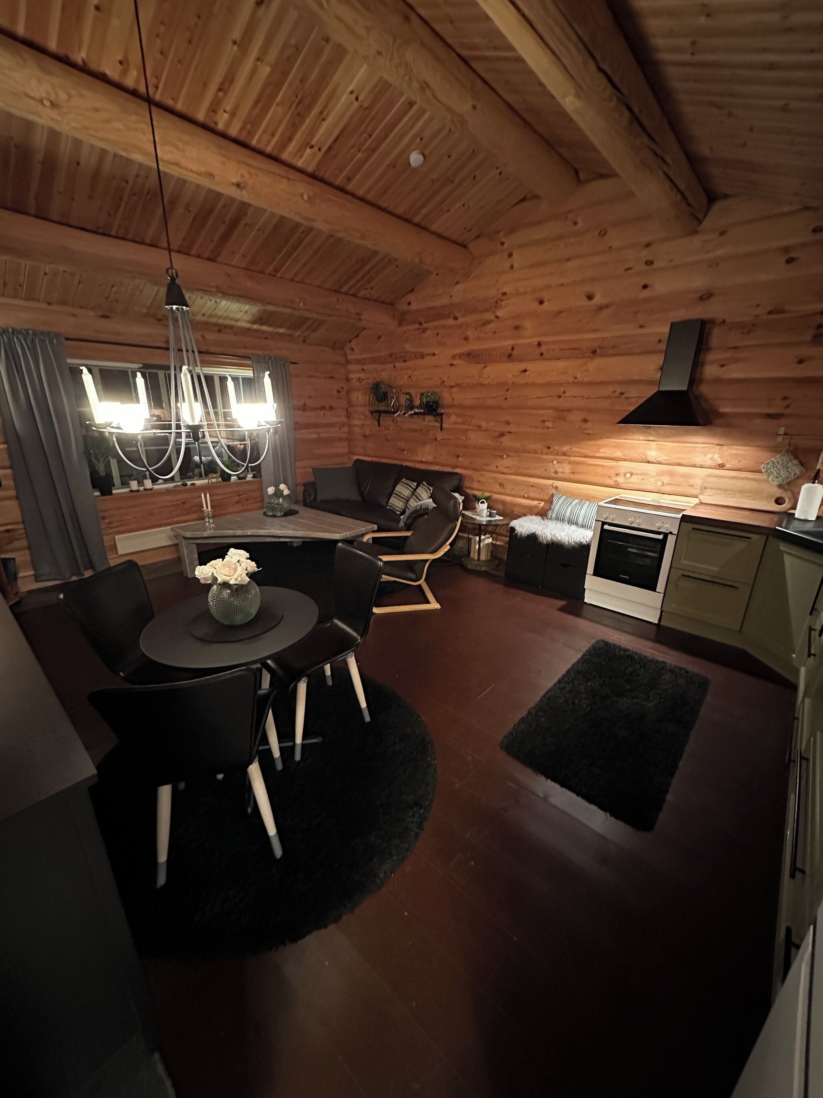 Een knus interieur van een blokhut met een eethoek, bank en kitchenette.