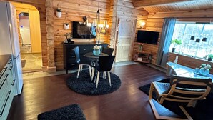 L’intérieur d’un chalet confortable, avec une salle à manger, une cuisine et une grande fenêtre.