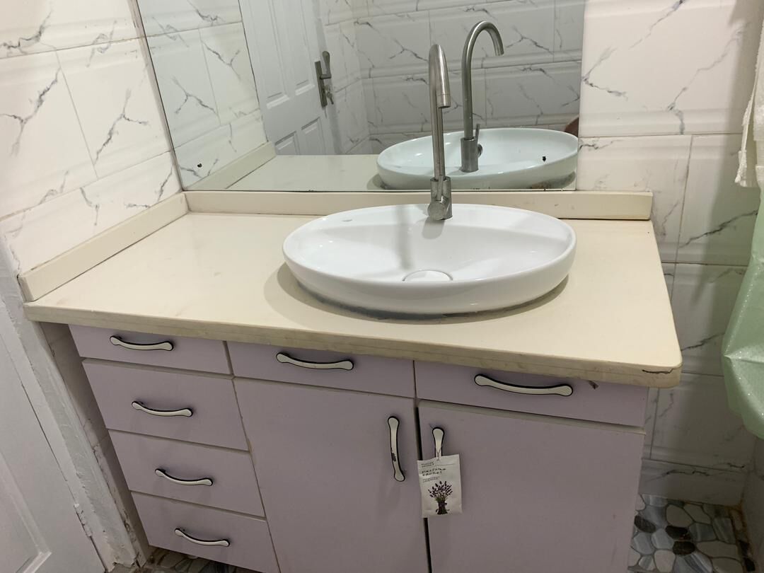 Un baño con un lavabo blanco, un espejo y un mueble con cajones.