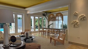 Un vaste espace de vie avec une grande porte vitrée donnant sur un balcon, des meubles en bois et une lampe moderne.