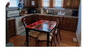 A kitchen with wooden cabinets, a stove, a microwave, and a dining table with chairs. - Entire House Quite Neighborhood (Kannapolis)