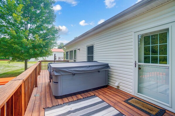 Un jacuzzi cubierto en una terraza de madera, con vista a una casa y un árbol.