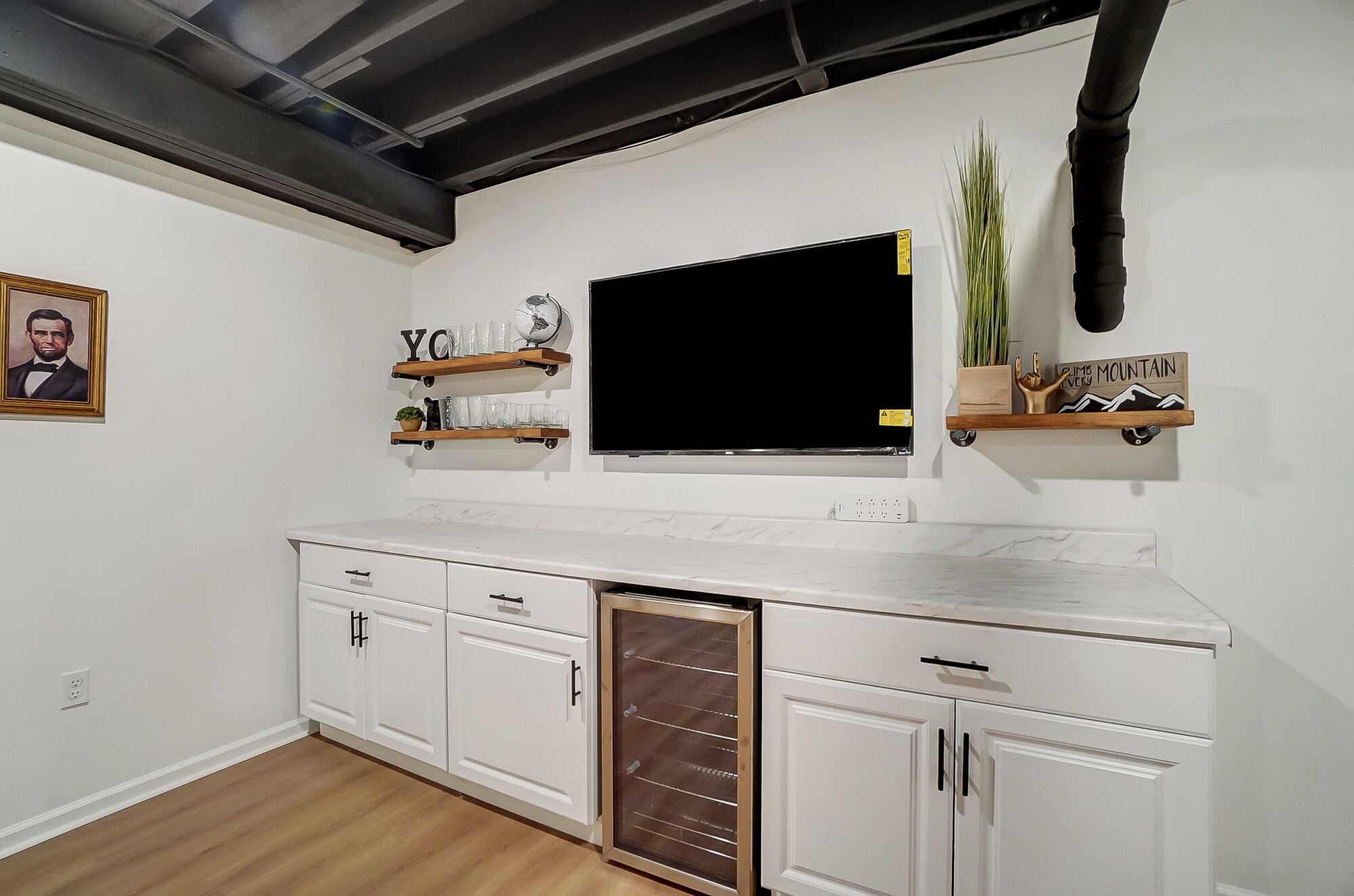 A kitchen with white cabinets, a marble countertop, a built-in oven, and a black ceiling vent.