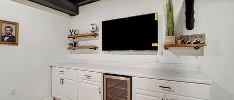 A kitchen with white cabinets, a marble countertop, a built-in oven, and a black ceiling vent.