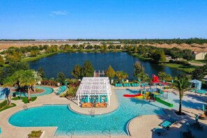 A large outdoor swimming pool with a water slide and a covered seating area.