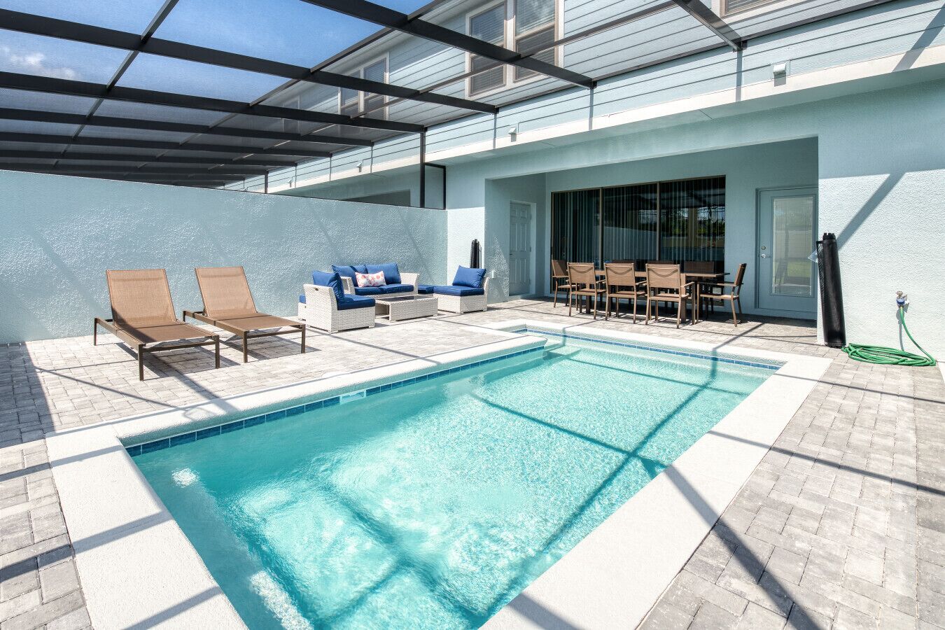 Une piscine entourée d’un patio couvert, avec des chaises longues et une table.