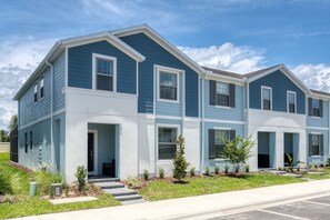A two-story residential building with a blue exterior, white trim, and a front entrance with steps.