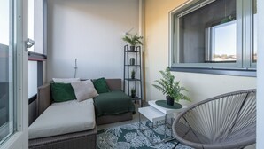 A small balcony with a wicker sofa, a chair, and potted plants. - Homelike 1BR Apt. with Sauna & Parking (Kuopio)