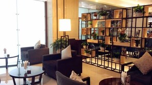 A modern hotel lobby with a seating area, a decorative bookshelf, and a large window. - Xi'an Zhongxing Hetai Hotel (Xi'an)