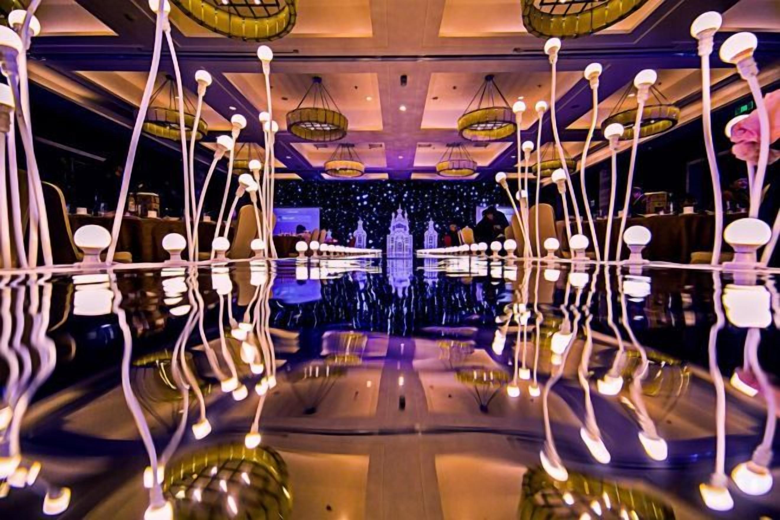 A room with a reflective floor, hanging light fixtures, and a central chandelier.