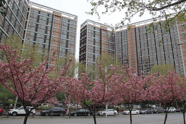 A parking lot with cars and a row of trees with pink blossoms. - Xi'an Zhongxing Hetai Hotel (Xi'an)