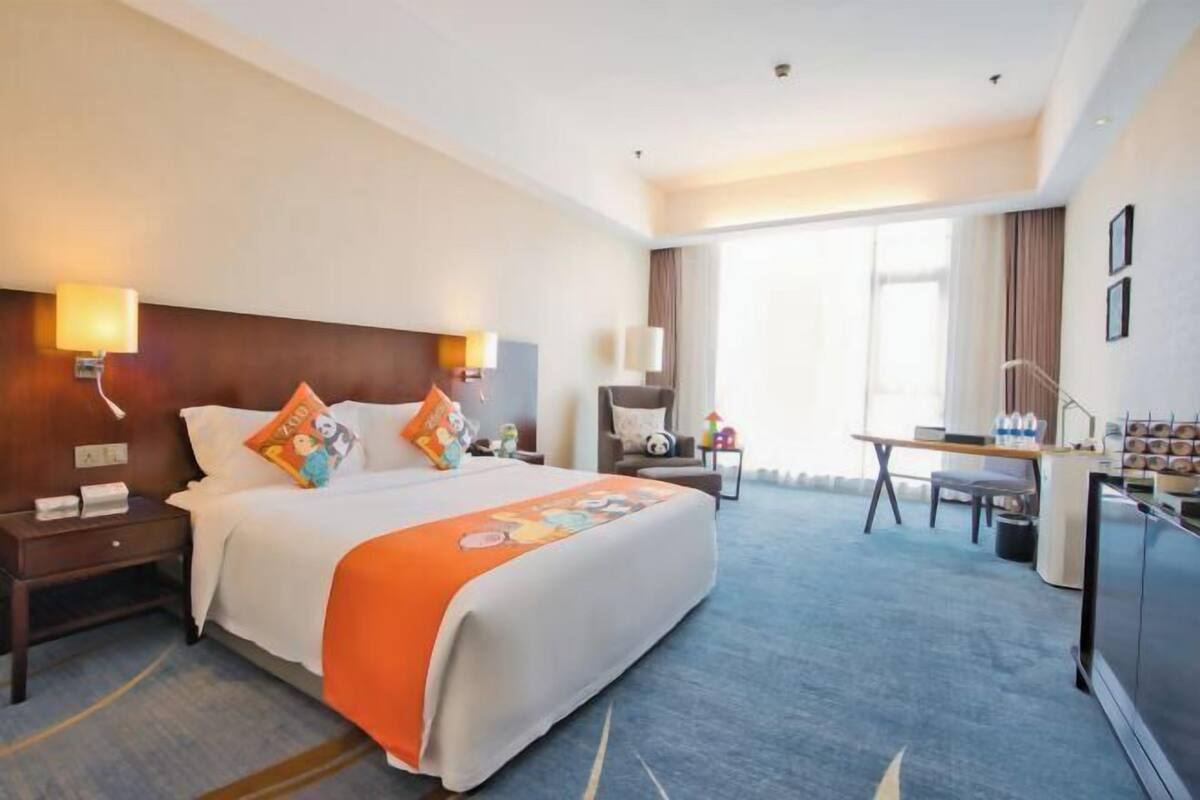 A hotel room with a large bed, bedside tables, a desk, and a chair.