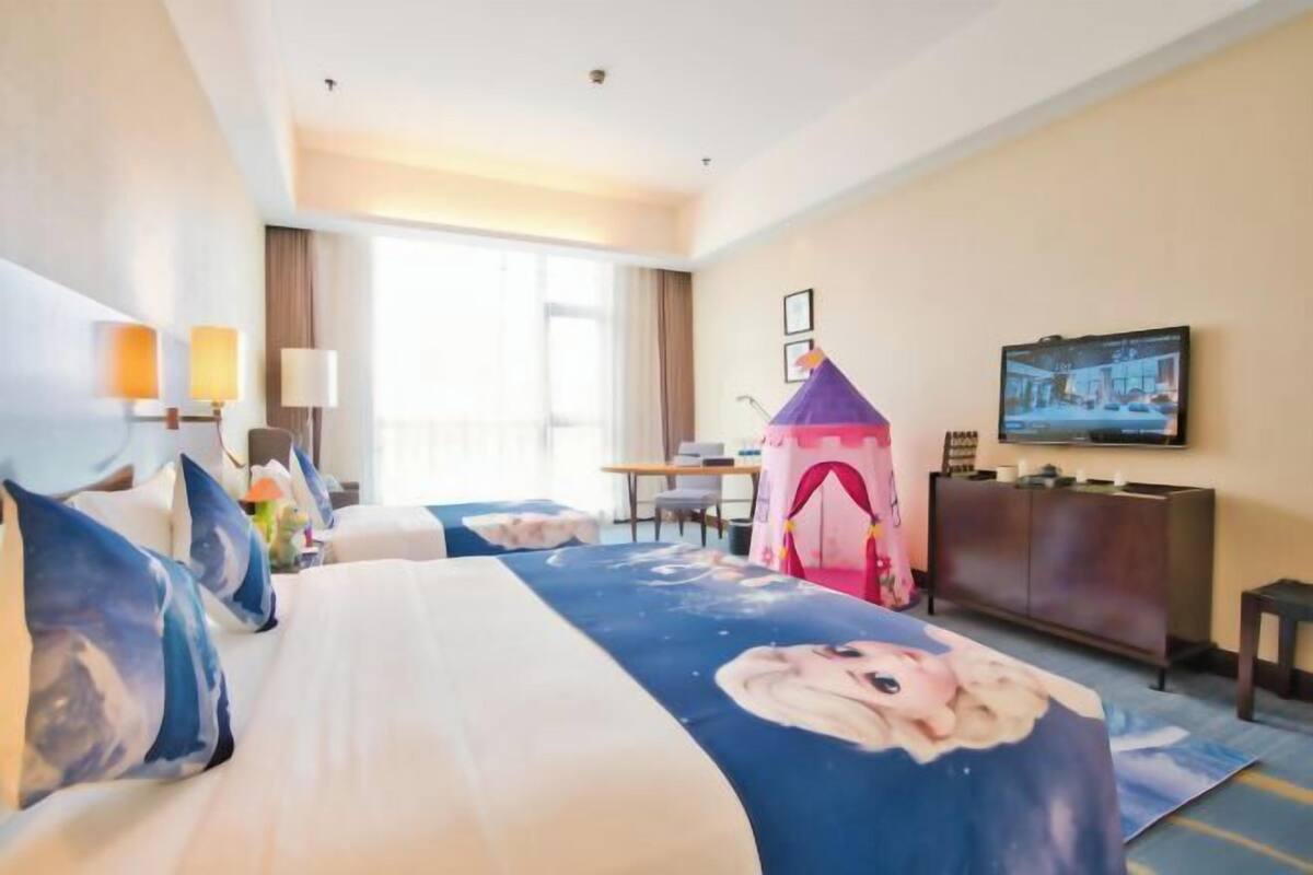 A hotel room with a bed, a desk, a television, and a window.