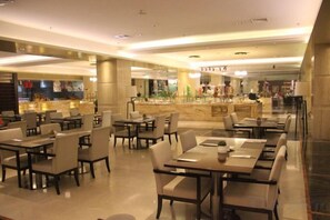 A spacious restaurant with multiple tables and chairs, a bar area, and a marble counter. - Xi'an Zhongxing Hetai Hotel (Xi'an)