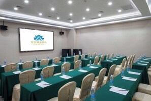 A conference room with rows of tables, chairs, and a projection screen displaying a logo. - Xi'an Zhongxing Hetai Hotel (Xi'an)