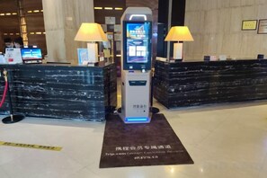 A reception area with a digital check-in kiosk, two lamps, and a marble reception desk. - Xi'an Zhongxing Hetai Hotel (Xi'an)